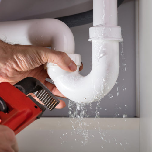 Close-up Of Male Plumber Fixing White Sink Pipe With Adjustable Wrench